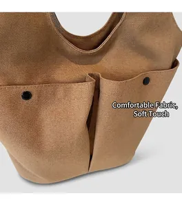 Close-up of canvas tote bag featuring double front pockets and black snap button details