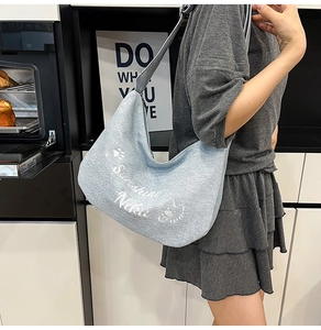 Vue détaillée du sac croissant en toile bleu clair avec broderie d'ours