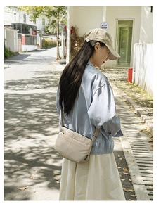 Détail du sac bandoulière en nylon beige avec plusieurs fermetures éclair et sangle