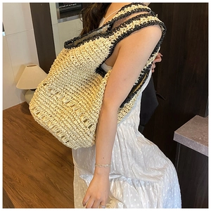 Detail view of handmade straw tote bag with black strap and hollow mesh weave design