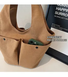 Detail of a brown canvas tote bag featuring double front pockets with a smartphone inside