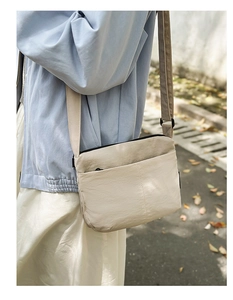 Vue d'un sac bandoulière beige léger avec une large bandoulière en tissu réglable
