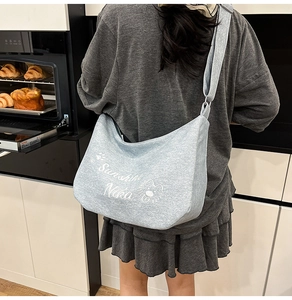 Détail du sac bandoulière gris-bleu clair avec imprimé lettres et texture tissu