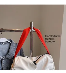 Detail of white nylon tote bag featuring durable handles and a vibrant orange strap