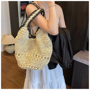 Detail of the woven straw shoulder bag with black contrast handles and beige texture