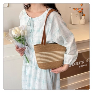 Detail of straw woven bucket bag with leather straps and white striped patterns