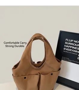 Detail of brown canvas tote bag featuring double front pockets with black snap fasteners