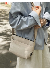 Détail du sac beige en nylon montrant l'étiquette de marque et la fermeture éclair