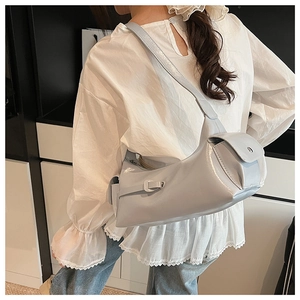 Detail view of glossy light grey shoulder bag featuring wide strap and side flap pocket