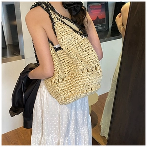 Detail of woven straw hobo bag with contrast black wavy trim and wide shoulder strap