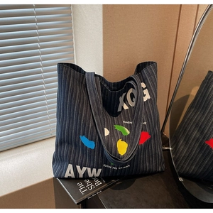 Close-up of denim tote bag with striped pattern and colorful artistic paint splashes