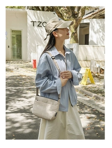 Photo en extérieur d'un sac bandoulière en nylon crème avec plusieurs poches zippées