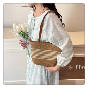 Detail of striped straw shoulder bag with brown leather strap and woven texture