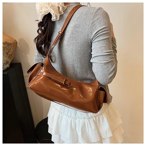Close-up of caramel brown glossy patent leather shoulder bag with side pocket detail