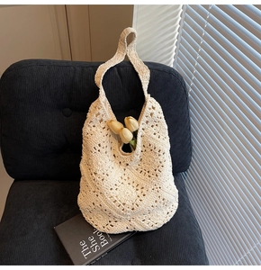 Gros plan du sac à bandoulière en crochet crème avec motif floral sur une chaise noire