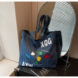 Detail of blue striped denim tote with colorful graffiti prints and sturdy canvas straps