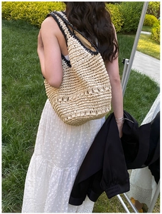 Detail of handmade straw hobo bag with black crochet trim on model in outdoor setting