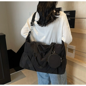 Detail einer großen schwarzen Nylon-Reisetasche mit rundem Beutel und Schultergurt