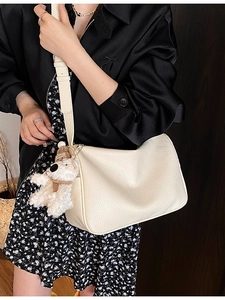 Schicke beige Unterarmtasche aus Leder mit niedlichem Bärenanhänger am Model