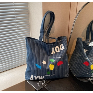 Detail of striped denim tote bag with colorful graffiti and inspirational text