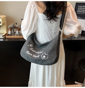 Sac demi-lune en toile gris foncé avec imprimé lion porté à l'épaule par un mannequin