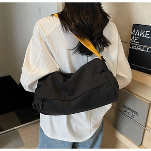 Rear view of a black fashion messenger bag with a vibrant yellow adjustable shoulder strap