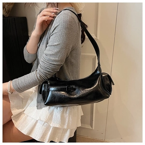 Close-up of black glossy underarm bag with side pockets and smooth leather texture