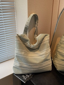 Green and white checkered canvas tote bag with textured stripes in soft natural light