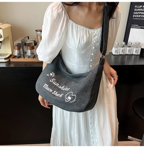 Détail du sac bandoulière en toile grise avec imprimé lion et sangle réglable au café