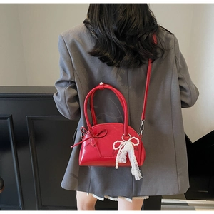 Dettaglio borsa rossa con fiocco, nappa di perle in pizzo e finitura lucida elegante