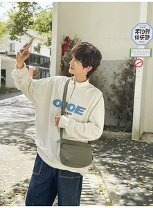 Style de rue montrant un sweat homme en maille gaufre avec un sac bandoulière blanc