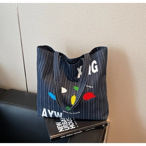 Detail showing blue striped canvas tote bag with artistic colorful graffiti and text