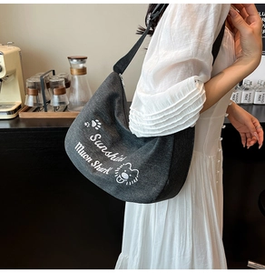 Détail du sac à bandoulière en toile grise avec imprimé lion et lettrage élégant