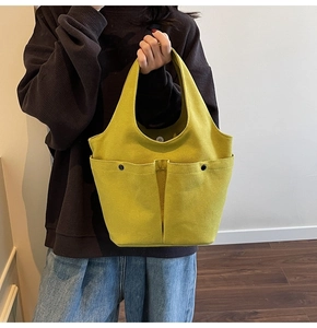 Detail of mustard yellow pleated tote bag featuring dual pockets and canvas texture