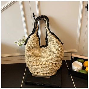 Detail of hand-woven straw tote bag with black contrast rope trim and sturdy handles