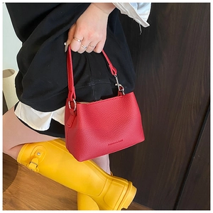 Dettaglio della borsa a secchiello rossa con trama litchi e logo moda per donna