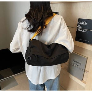 Detail of black sporty pillow bag with bright yellow strap shown on a model