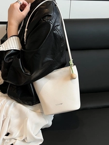 White pebbled leather bucket bag with wood bead charm and minimalist CLEANUK logo