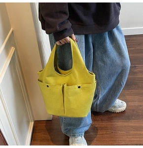 Model wearing a bright yellow pleated canvas tote bag with two front pockets
