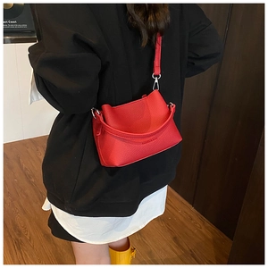 Détail du sac bandoulière rouge avec texture grainée et lettrage en relief