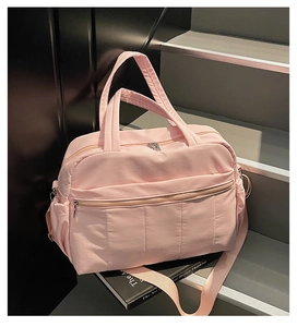 Pink travel bag detail showing quilted front pocket and adjustable shoulder straps