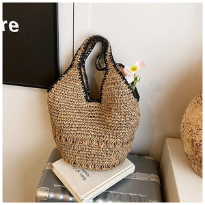 Detail of hand-woven straw tote bag with black trim on a vintage silver suitcase