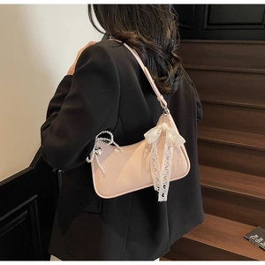 Dettaglio borsa sottospalla rosa con fiocco in pizzo e catena di perle su modella