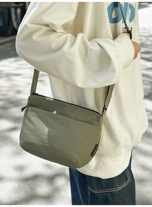 Sac bandoulière décontracté vert olive en nylon porté par un mannequin en extérieur