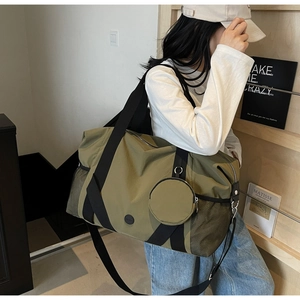 Olivgrüne Reisetasche mit Schultergurt und Mini-Rundbeutel, am Modell präsentiert