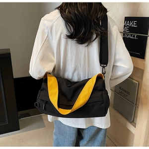 Detail of minimalist black and yellow crossbody bag with adjustable strap worn by model