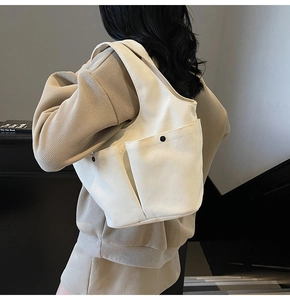 Model view showing the back profile of the off-white pleated canvas tote bag with side pockets