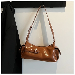 Detail of glossy brown faux leather shoulder bag with side pockets and buckle on a hook