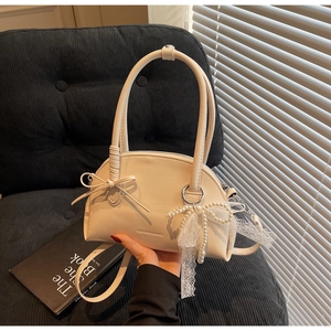 Dettaglio borsa beige con elegante fiocco di perle e pizzo con manico superiore