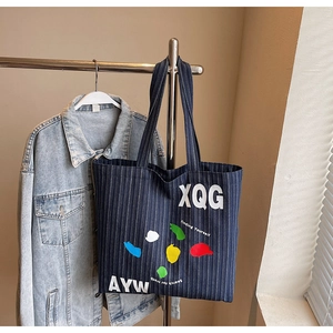 Detailed shot of large denim tote bag featuring striped pattern and artistic lettering prints